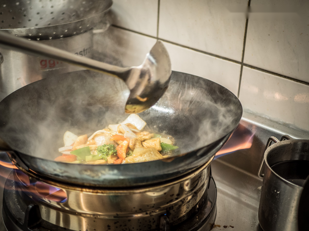 Gemüse und weitere Zutaten werden im Wok gebraten